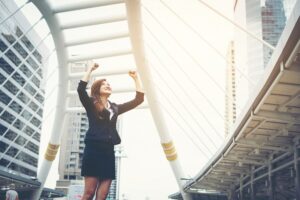 happy success businesswoman overlooking into city center hands raised 1150 2516